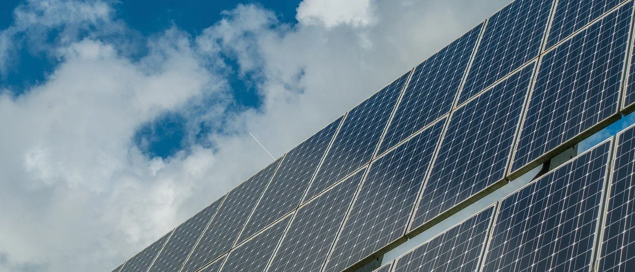 A solar array photographed from below against a bright sky
